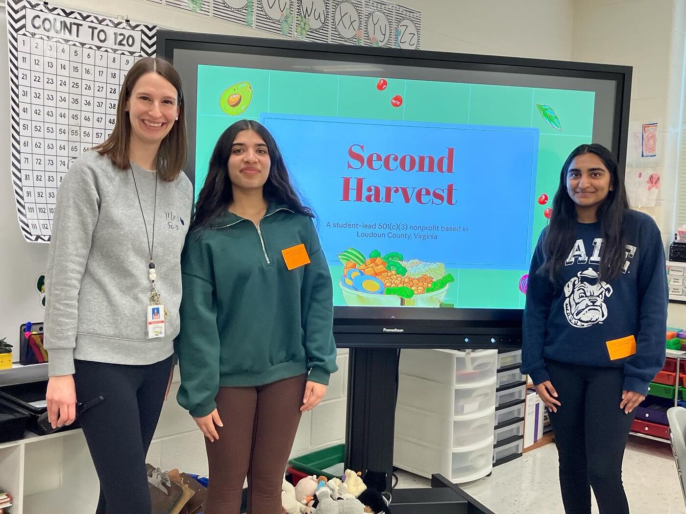 Two Second Harvest ambassadors with a teacher in front of their Second Harvest presentation